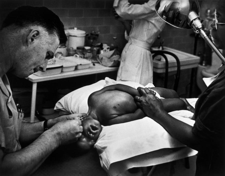 W. Eugene Smith: „Maude Callen padeda vietiniam gydytojui operuoti vaiką“ Šiaurės Karolina, JAV, 1951.